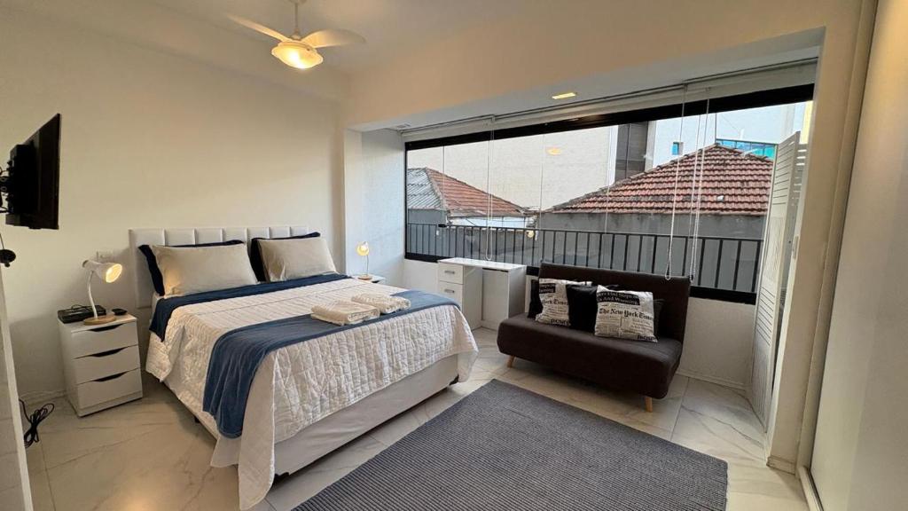 sypialnia z łóżkiem i krzesłem oraz dużym oknem w obiekcie Seu Refúgio Urbano na Bela Vista w São Paulo