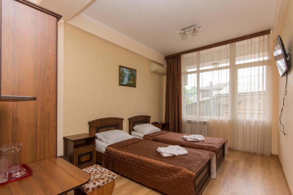 a hotel room with two beds and a window at Palmira Guest House in Adler