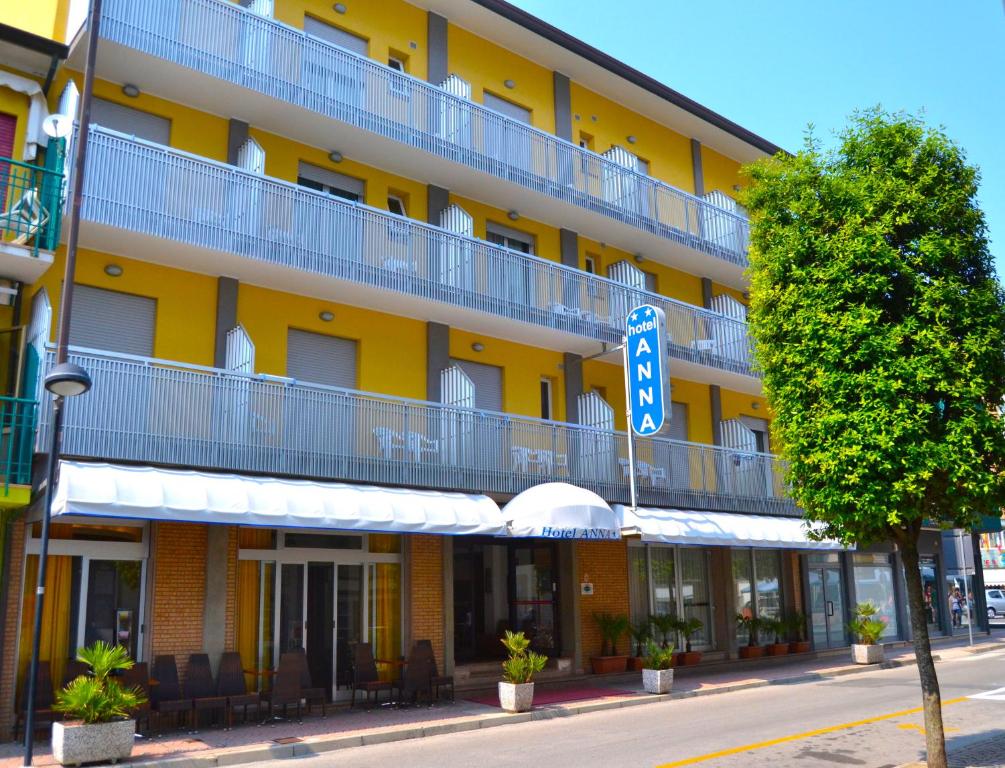 un bâtiment jaune avec un panneau de rue devant lui dans l'établissement Hotel Anna, à Caorle