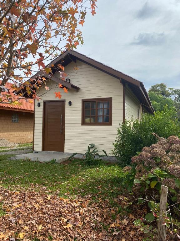 a small white house with a brown door at Chalé do Vale in São Francisco