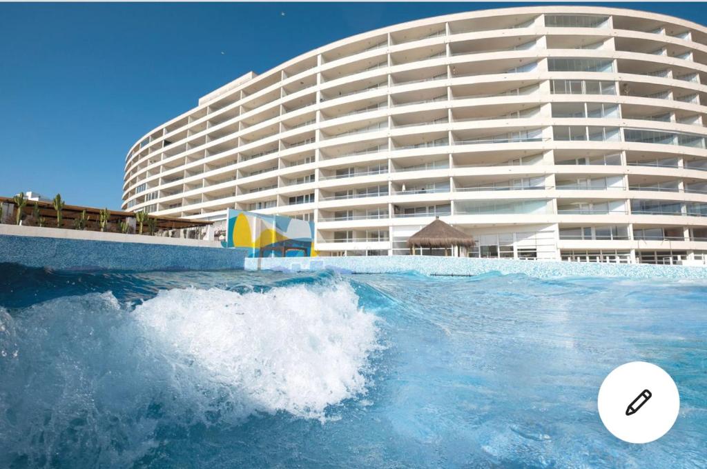 a large building next to a wave in the ocean at Acogedor Dpto, Playa y Piscinas in La Serena