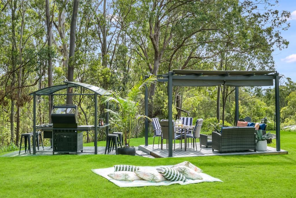 a man sitting on a bench under a gazebo at Stylish, Scenic Rural Retreat in Upper Caboolture
