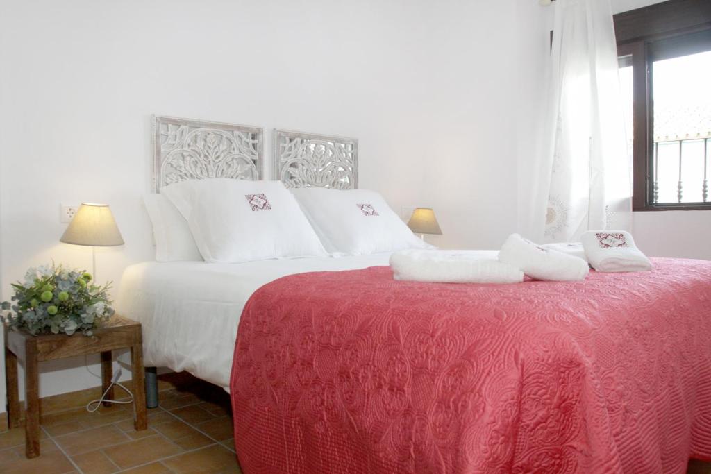 un lit blanc avec des oreillers blancs et une couverture rouge dans l'établissement Apartamentos San Fernando 76, à Cordoue