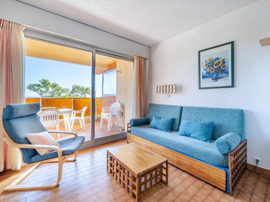 un salon avec un canapé bleu et un balcon dans l'établissement Appartement pour 8, spacieux séjour, vue mer, Wi-Fi inclus - FR-1-827-20, à Roquebrune-Cap-Martin