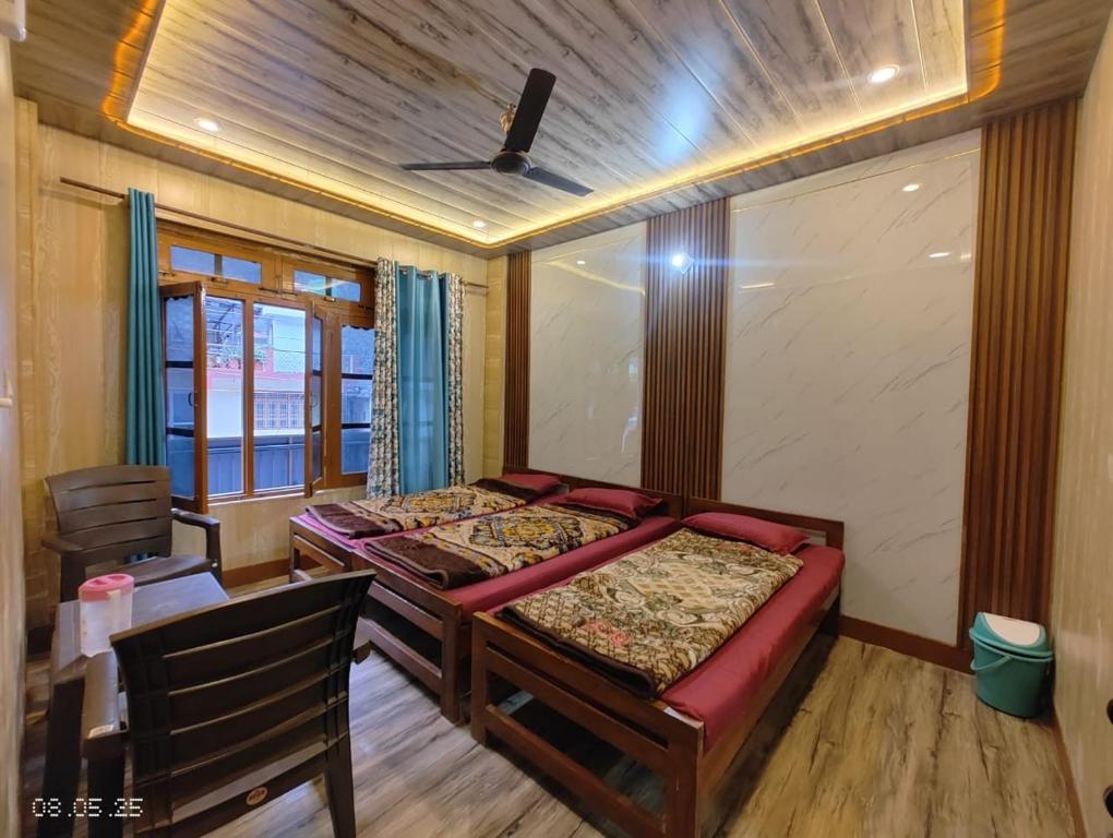 a bedroom with two beds and a table and a window at Gokul Guest House By Mero Pahad Stays & camp in Pāndukeshwar