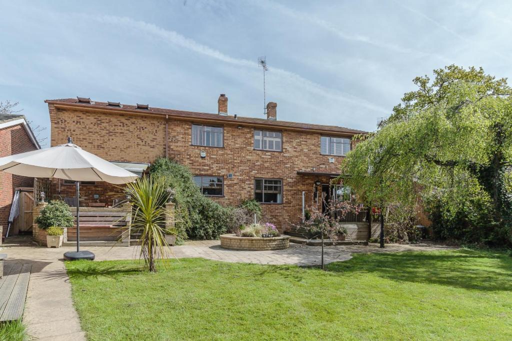 a brick house with an umbrella in the yard at Richmond Lane Guest House - AA Accredited in Romsey