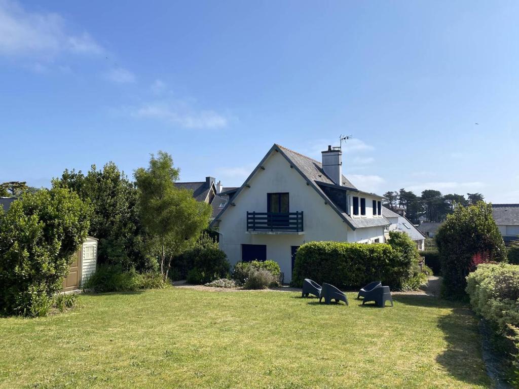 une maison blanche avec deux bancs dans la cour dans l'établissement Bel appartement rénové avec vue mer à Trégastel, proche plage - FR-1-368-462, à Trégastel