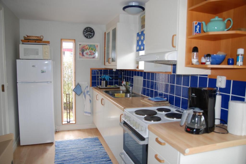 a kitchen with blue tiles on the walls and a stove at Badstugan in Karlshamn