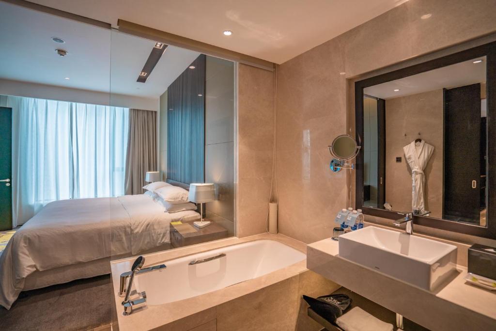 a bathroom with a bed and a tub and a sink at Four Points by Sheraton Changchun Hi-Tech Zone in Changchun