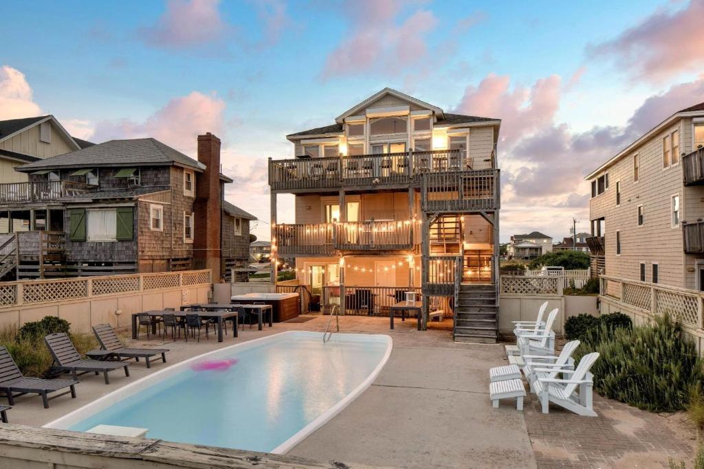 a house with a swimming pool next to a building at Sleeps 28 Beachfront w Pool Hot Tub Game Room Atlantic Watch by AvantStay in Kill Devil Hills