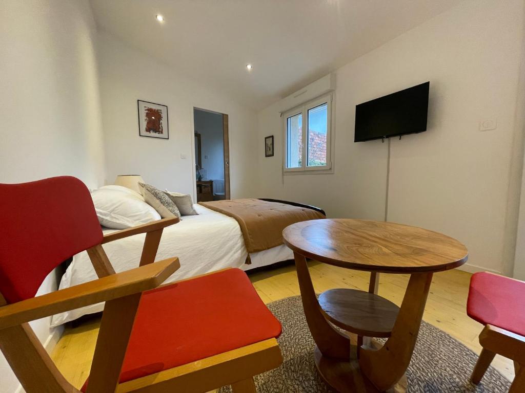 une petite pièce avec un lit et une table et un lit et une télévision dans l'établissement Chambre cosy dans le Centre de Blaye - clim - air con, à Blaye