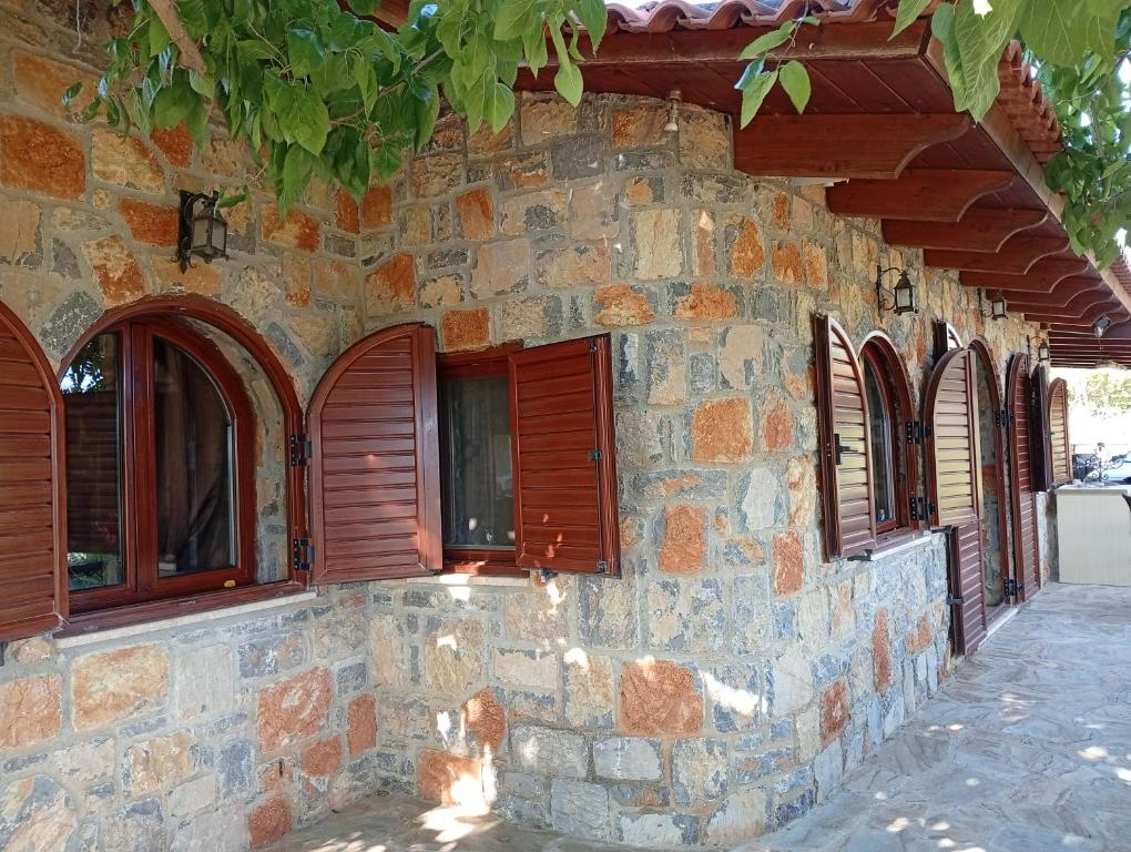 a stone building with brown windows and wooden shutters at Villa Despoina in Amarinthos