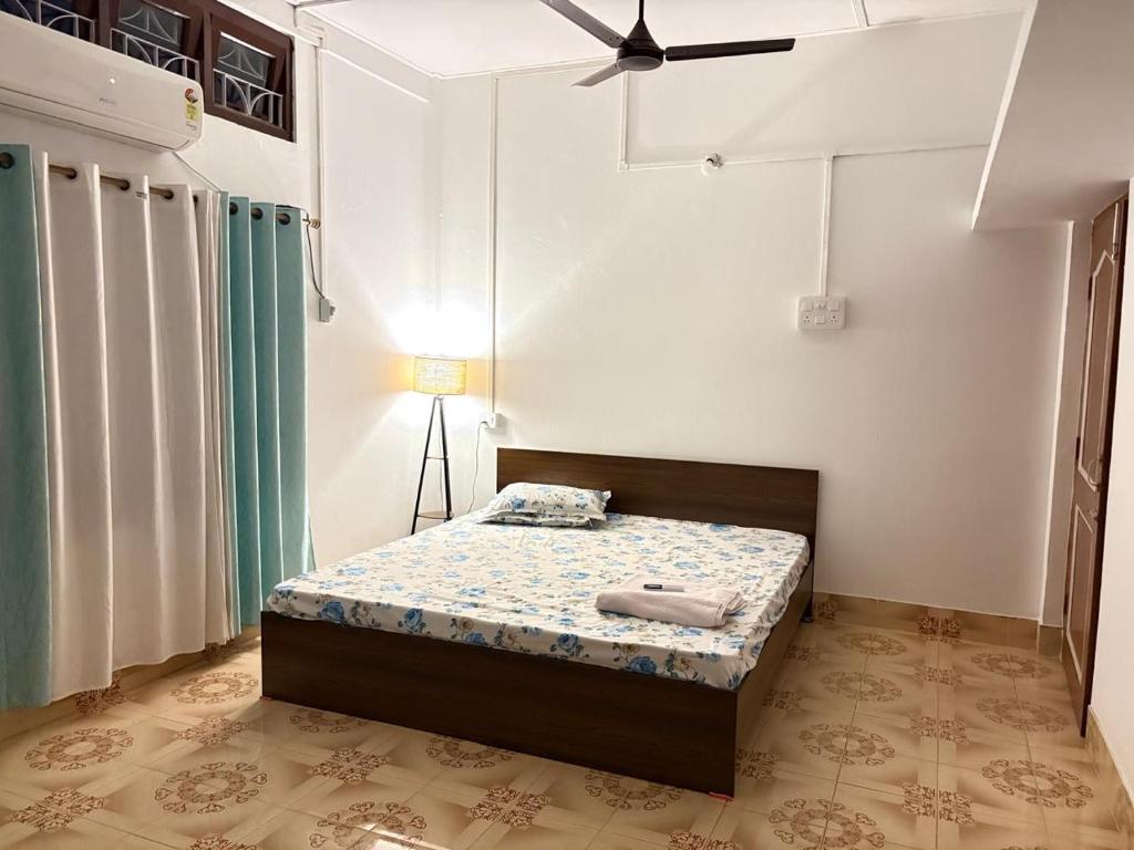 une chambre avec un lit et un ventilateur de plafond dans l'établissement Maadhuban Home Stay, à Dibrugarh