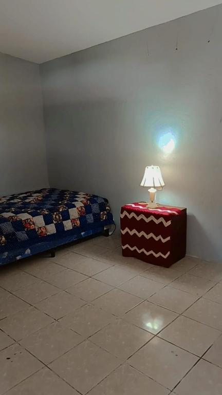 a bedroom with a bed and a table with a lamp at Lirio green hostal in Managua