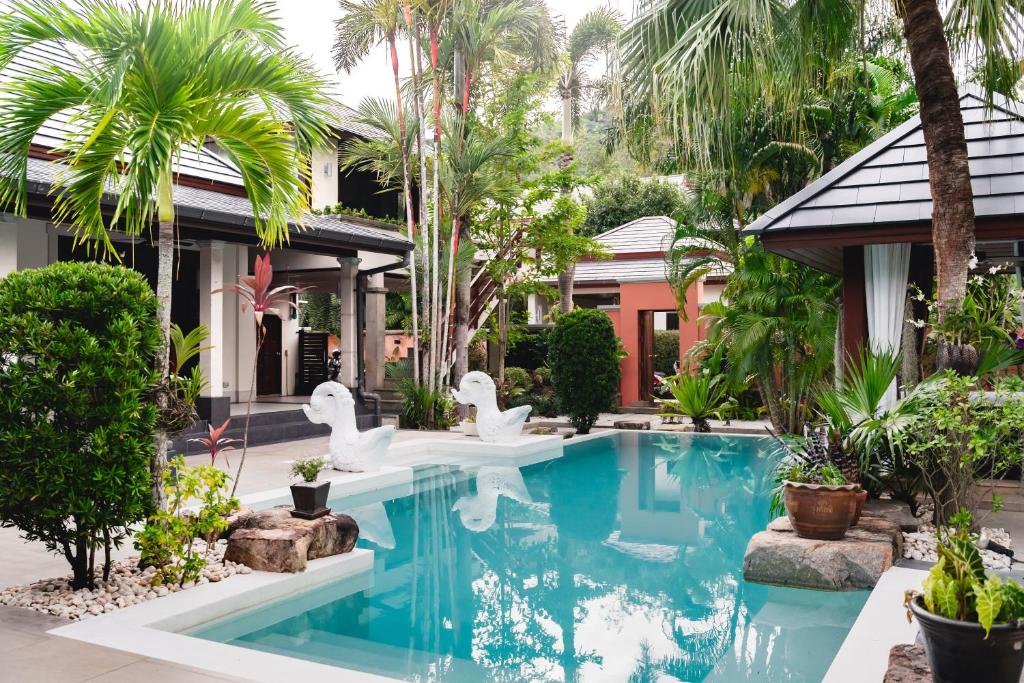a swimming pool in front of a house with white swans at Villa Banyak | Luxury 4Br villa with nice terrace and personal playground in Ban Saiyuan (1)