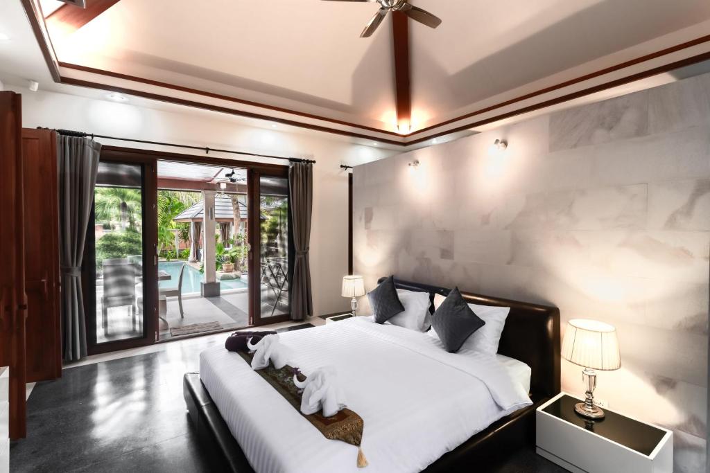 a bedroom with a large bed and a large window at Villa Banyak | Luxury 4Br villa with nice terrace and personal playground in Ban Saiyuan (1)