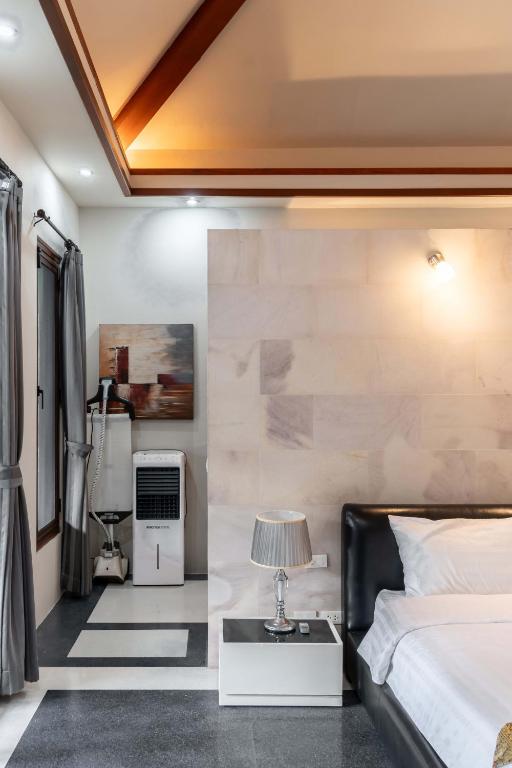 a bedroom with a bed and a table with a lamp at Villa Banyak | Luxury 4Br villa with nice terrace and personal playground in Ban Saiyuan (1)