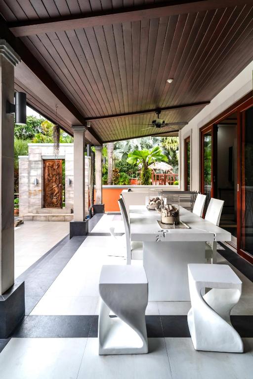 an outdoor patio with white tables and chairs at Villa Banyak | Luxury 4Br villa with nice terrace and personal playground in Ban Saiyuan (1)