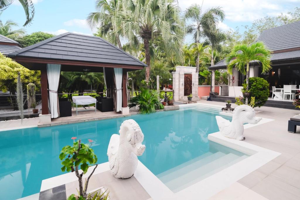 a pool with white elephant statues next to a house at Villa Banyak | Luxury 4Br villa with nice terrace and personal playground in Ban Saiyuan (1)