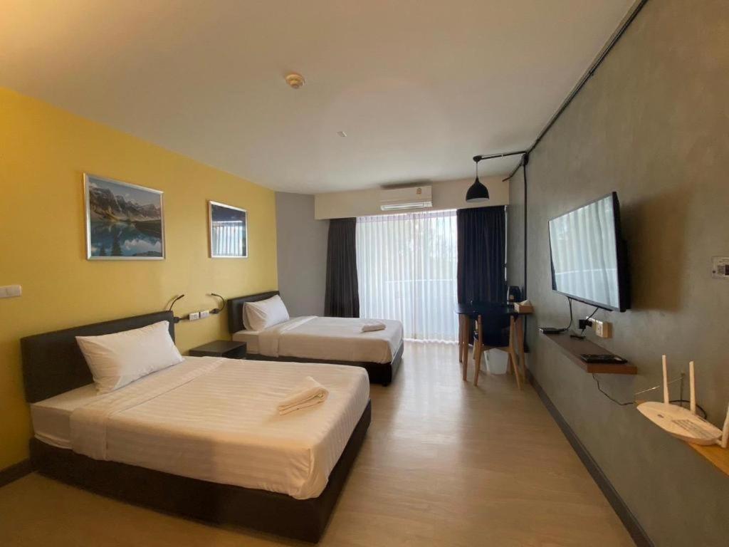 una habitación de hotel con dos camas y un televisor de pantalla plana en DLUXX THAMMASAT, en Ban Bang Phut (3)