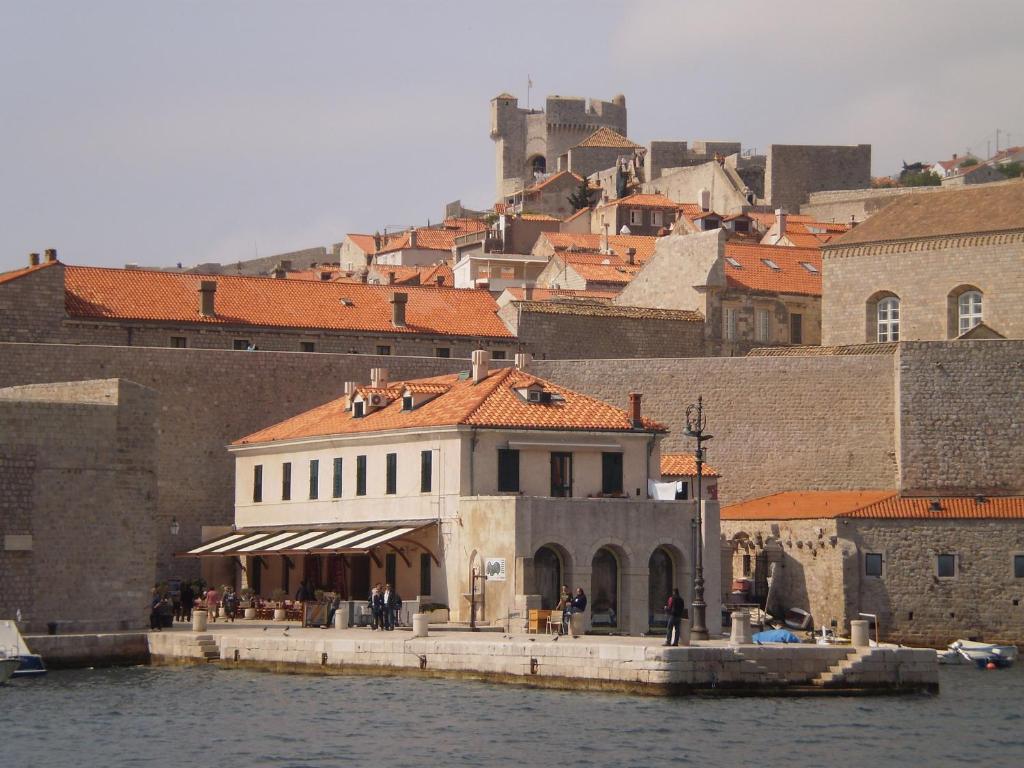 a building next to the water in front of a city at Dubrovnik OLD PORT Accommodation in Dubrovnik