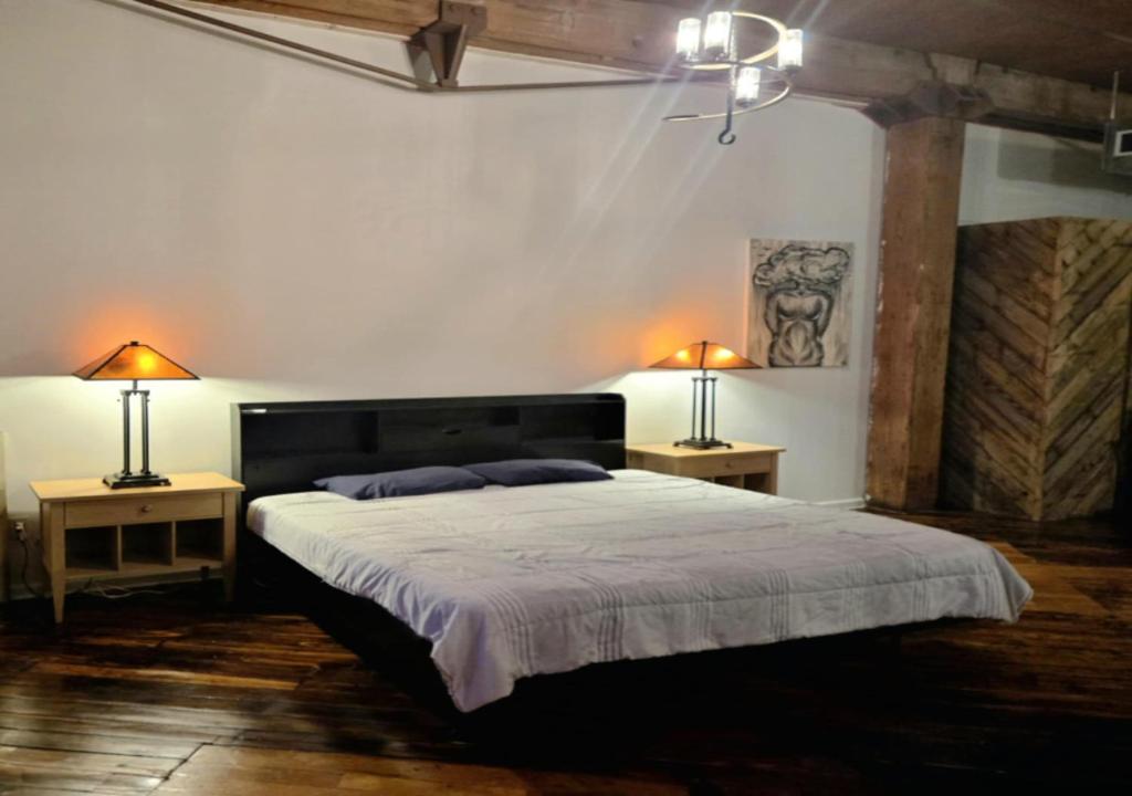 een slaapkamer met een groot bed met 2 lampen op 2 tafels bij Motown Riverfront Studio Loft in Detroit