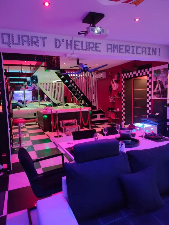 a room with couches and a stage with purple lights at LE QUART D'HEURE AMERICAIN in Bailleul