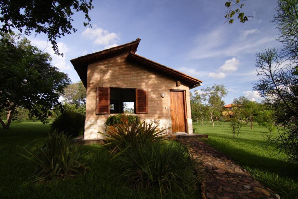 a small brick house with a door in a field at Pousada Vale das Araras in Cavalcante