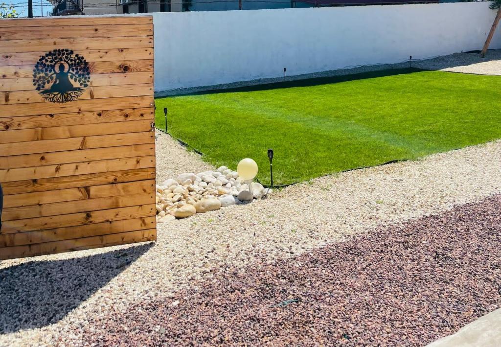 a wooden fence with a pile of rocks next to a lawn at Daro tiny house in Vama Veche