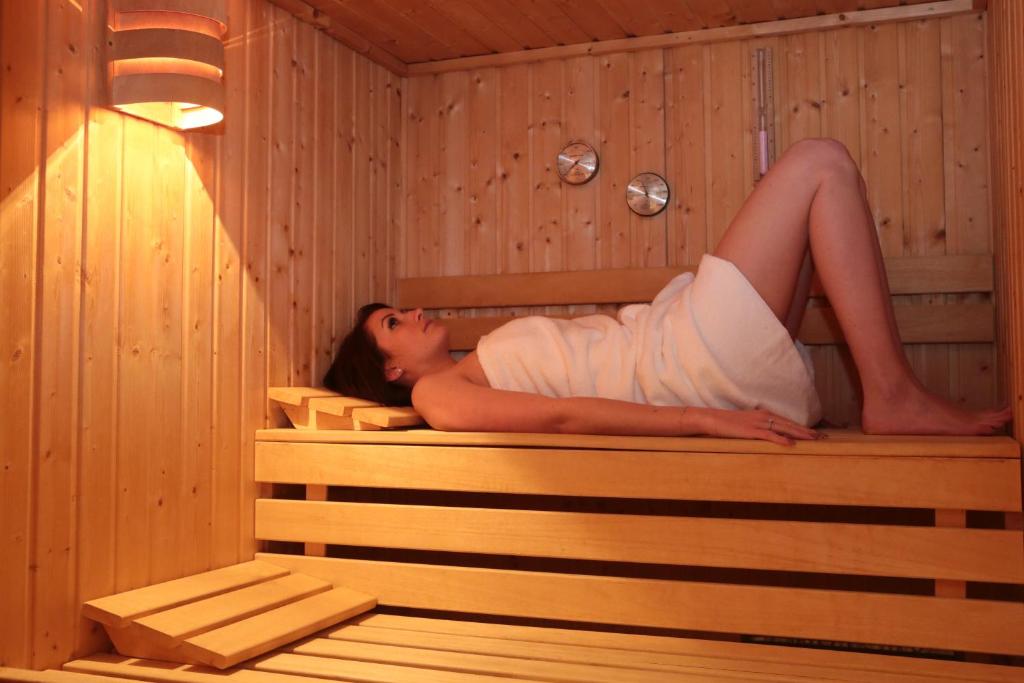 a woman is laying in a sauna at Hotel Le Mandelberg in Mittelwihr