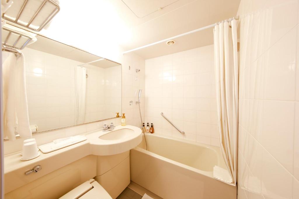 a white bathroom with a sink and a bath tub at Hotel the Lutheran in Osaka
