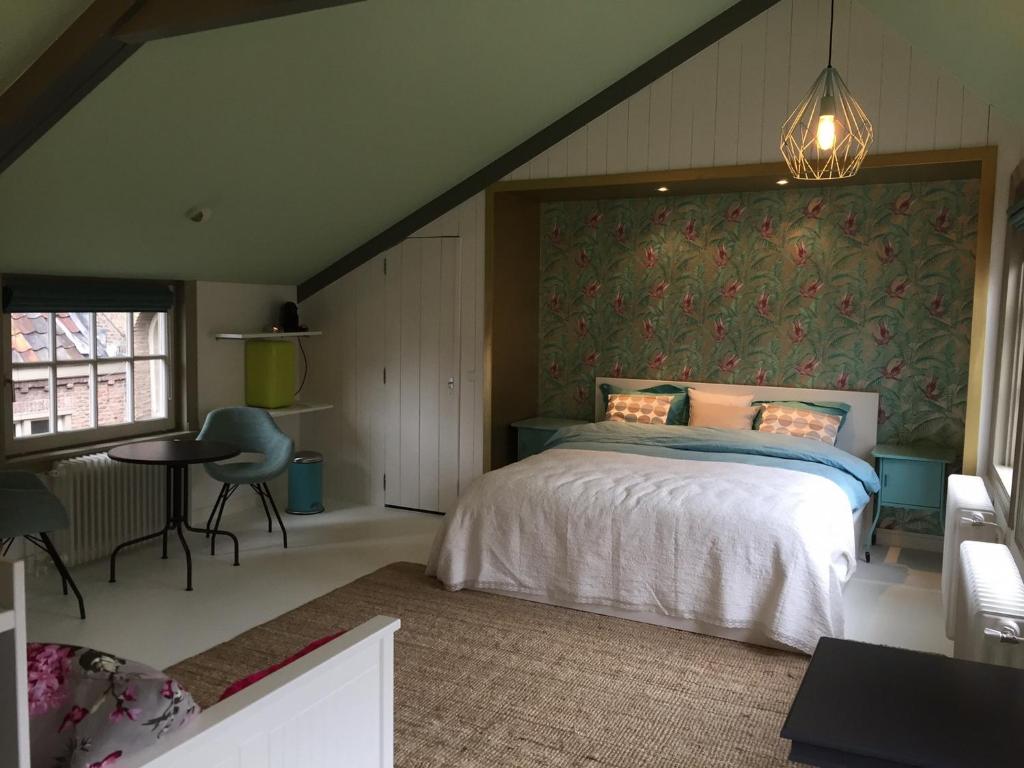 ein Schlafzimmer mit einem Bett, einem Tisch und einem Stuhl in der Unterkunft Heer&Meester Bed&Breakfast in Dordrecht