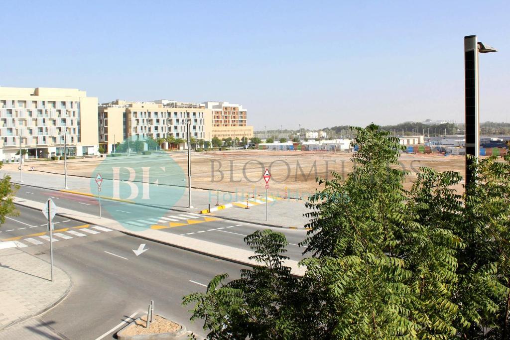 an empty street in a city with buildings at Bloomfields Stu With Balcony Leonardo Masdar City in Al Qurayyah