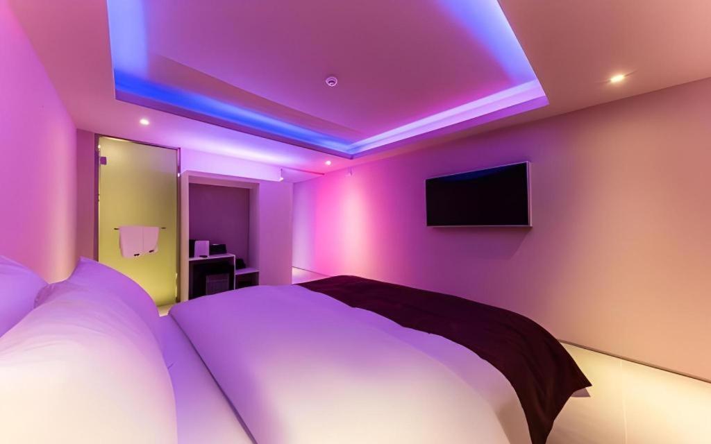 ソウルにあるBobo Hotel Hongdaeの壁に紫色のライトがありベッドがある寝室