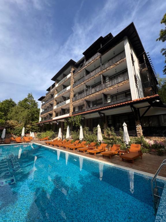 a hotel with a swimming pool with chairs and a building at Green apartments in Primorsko