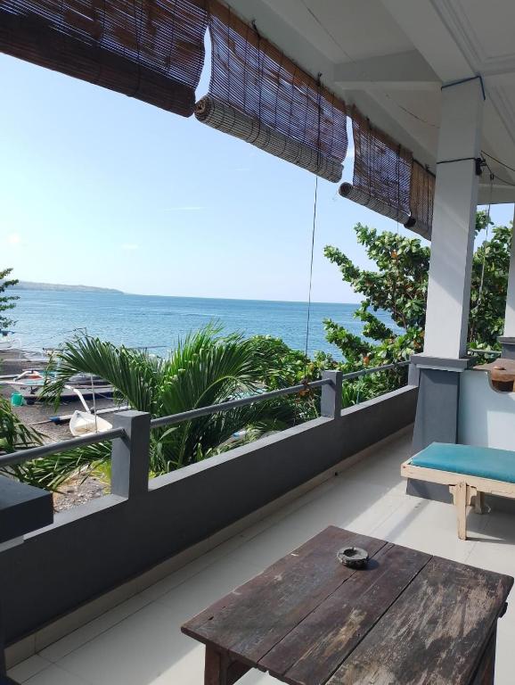 a balcony with a table and a view of the ocean at Kadek Homestay in Amed