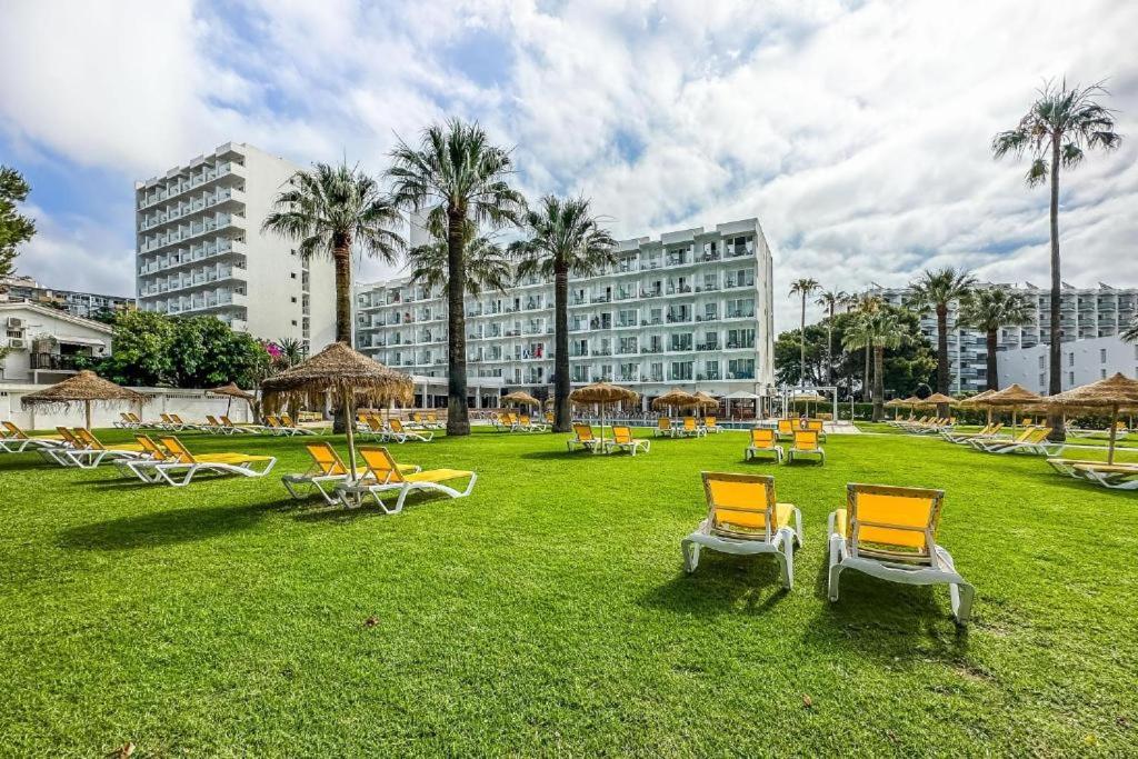 a park with chairs and umbrellas and a building at The Seven Seas in Benalmádena