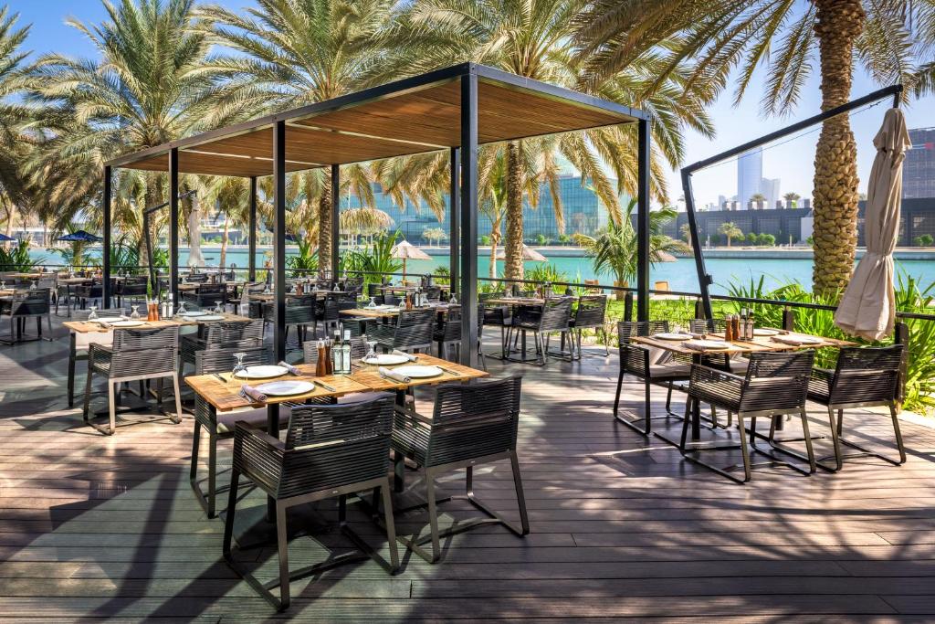 a restaurant with tables and chairs and palm trees at Beach Rotana - Abu Dhabi in Abu Dhabi