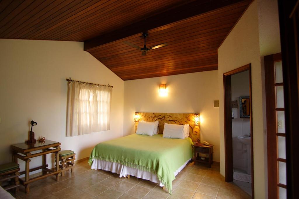 a bedroom with a green bed with a wooden ceiling at Pousada Vale das Araras in Cavalcante