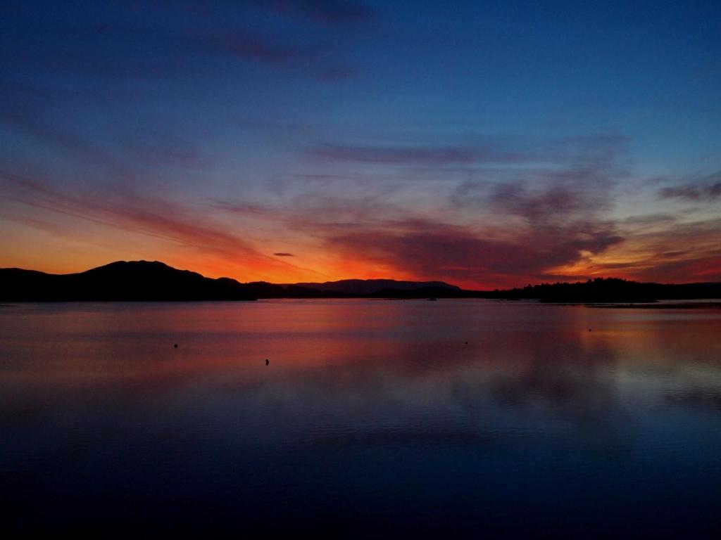 a sunset over a large body of water at The Inn on Loch Lomond in Luss