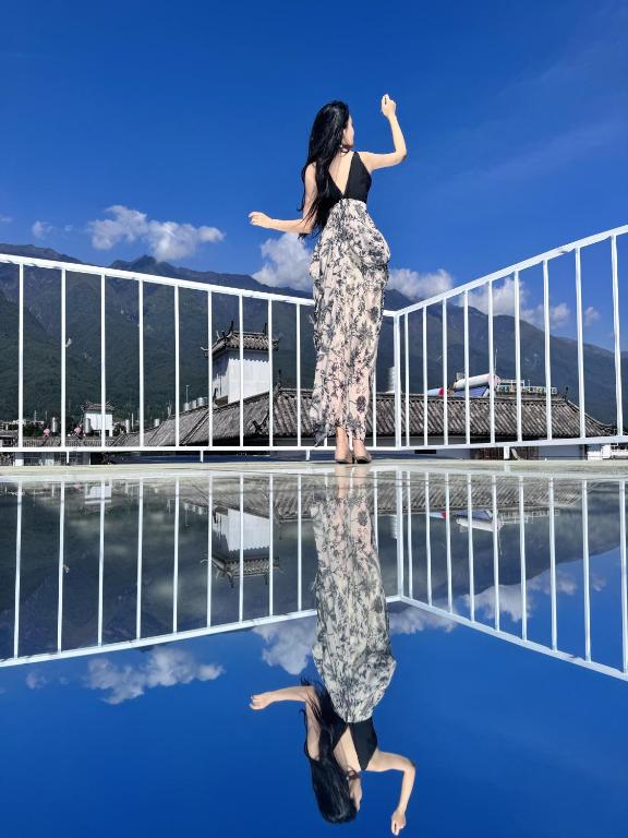 a woman standing on the edge of a pool at SIXI CANGSHAN MOUNTAINS GOLDEN SUNRISE MIRROR OF THE SKY SOUND SLEEP HOTEL DALI ANCIENT CITy in Dali