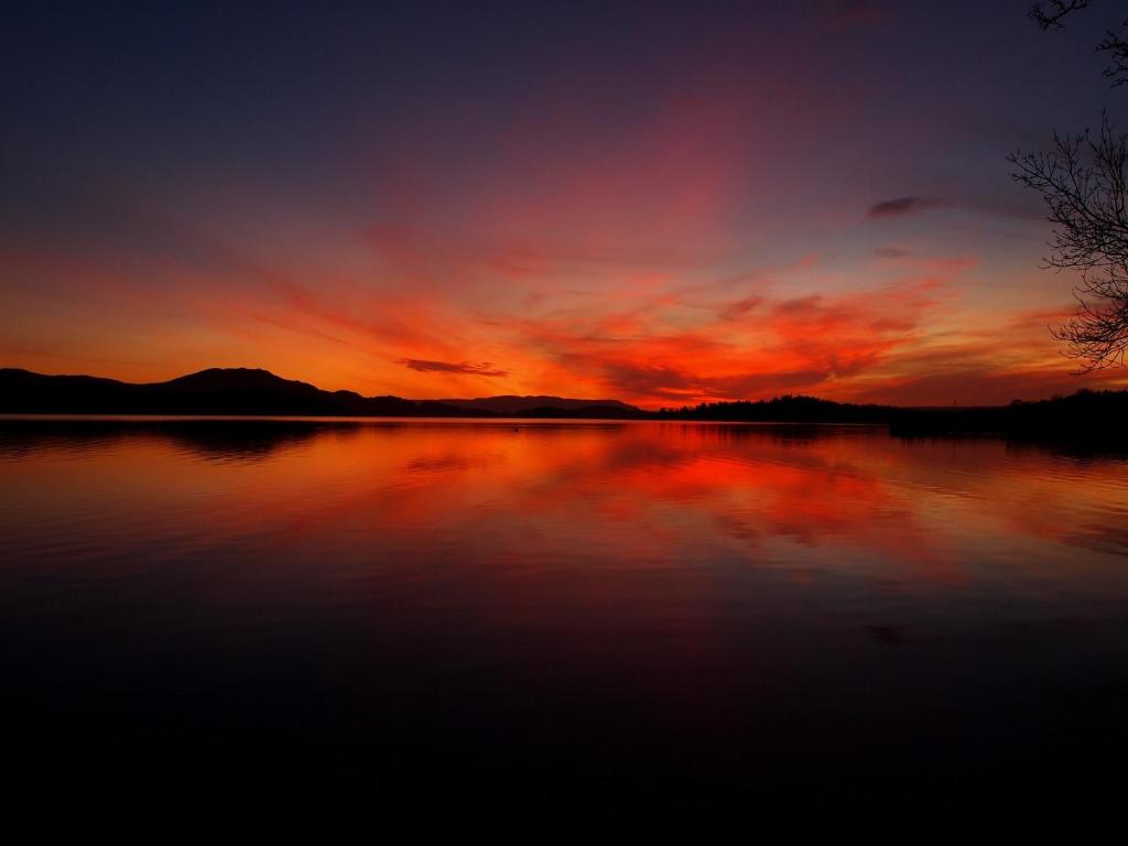 a sunset over a body of water with the sky at The Inn on Loch Lomond in Luss