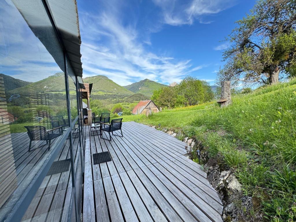 a wooden deck with benches and a view of mountains at La Guinguette de Lus in Lus-la-Croix-Haute