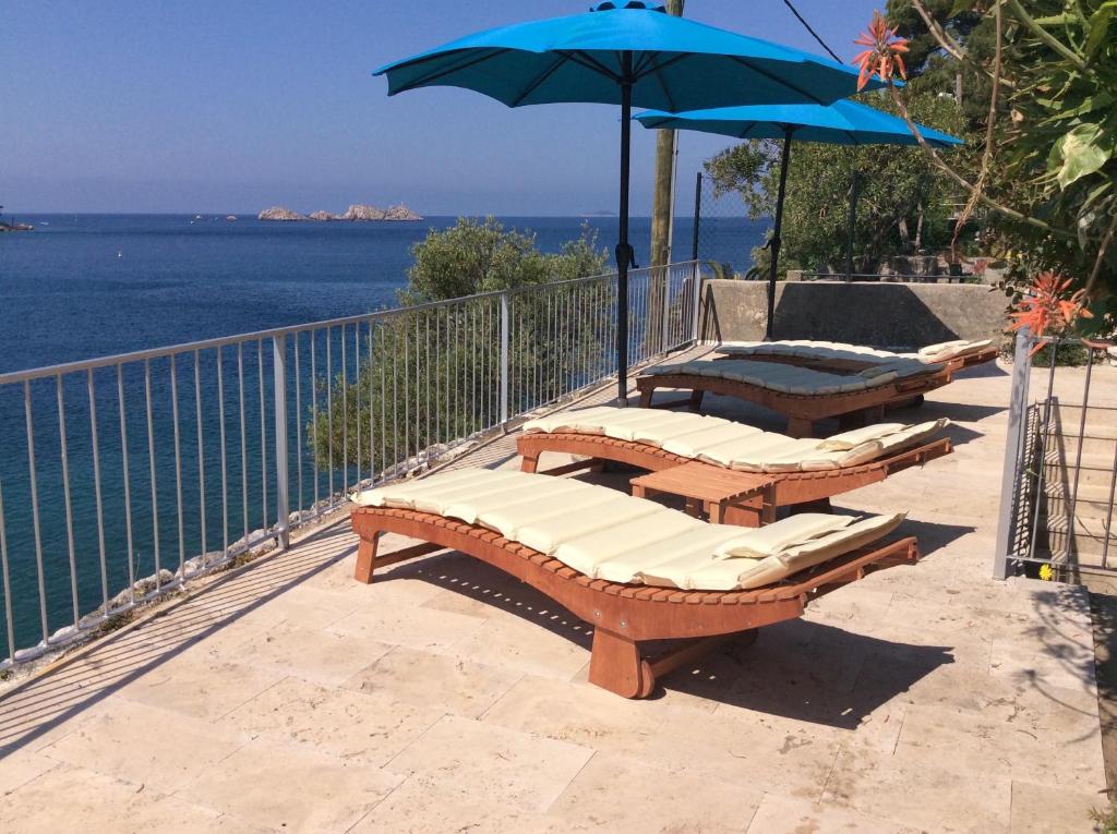 three lounge chairs and an umbrella on a balcony with the ocean at Dubrovnik Apartments in Dubrovnik