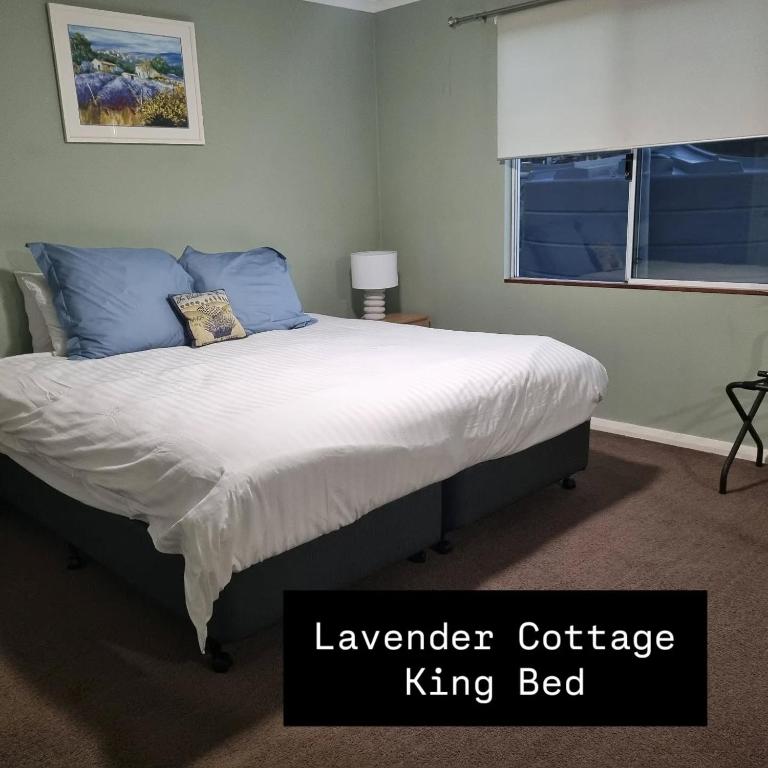 a bedroom with a king bed with blue pillows at Lavender Cottage at Nannup Lavender Farm in Nannup Mill