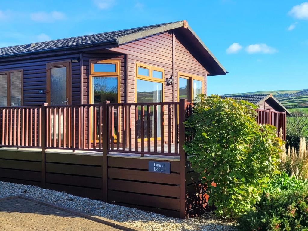 a small wooden cabin with a wooden fence at Laurel Lodge in Tintagel