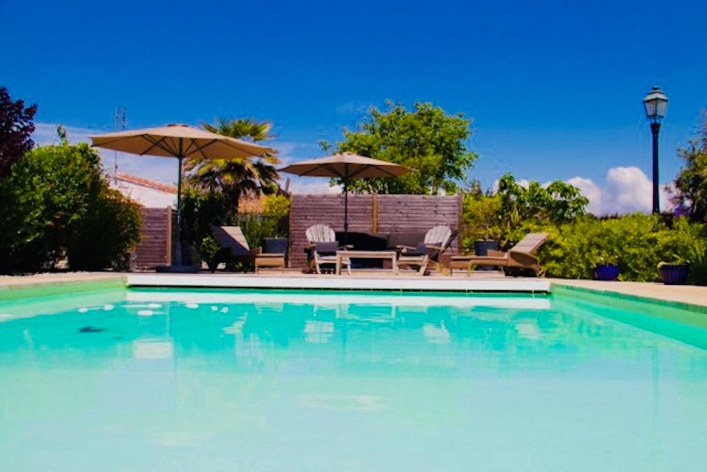 une piscine avec chaises et parasols dans l'établissement Flocon de Sel, à Sainte-Marie de Ré
