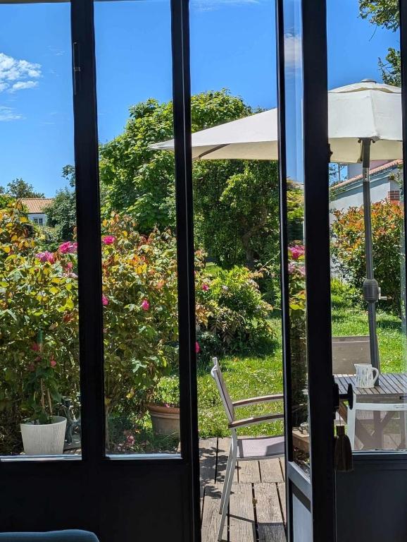 Une porte ouverte s'ouvre sur une terrasse avec une table et une chaise. dans l'établissement La petite Rêverie, à Pornic