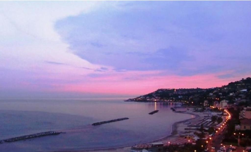 Blick auf einen Strand bei Nacht mit rosa Himmel in der Unterkunft Le case di Sara - Green Palm in Arma di Taggia