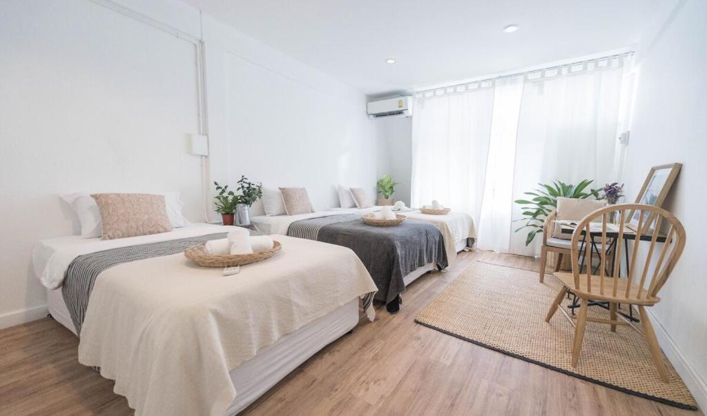 a bedroom with two beds and a table and a couch at The Ombra Small House No.2 in Chiang Mai